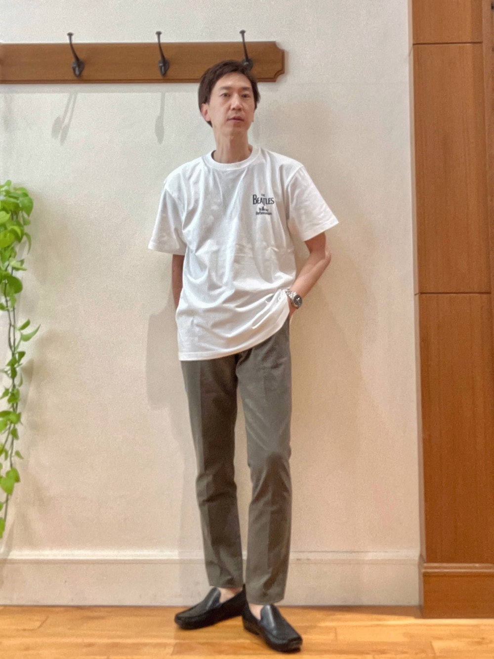 グリーン系のチノパンツ、ブラック系のショルダーバッグ、ホワイト系のTシャツ/カットソーを着用したメンズの春コーディネートの2枚目の写真