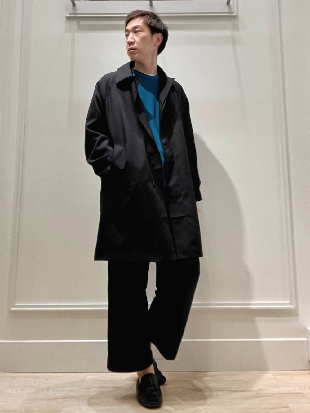 ブラック系のステンカラーコート、グリーン系のニット/セーターを着用したメンズの冬コーディネートの4枚目の写真