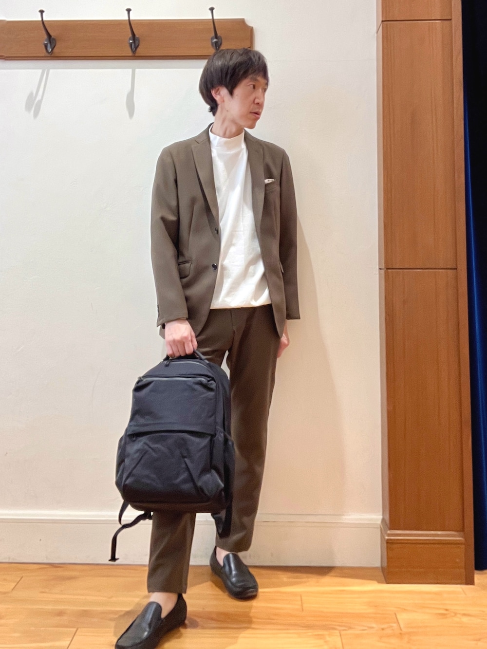 ブラウン系のテーラードジャケット、ブラック系のバックパック/リュック、ブラウン系のその他パンツを着用したメンズの春コーディネートの9枚目の写真