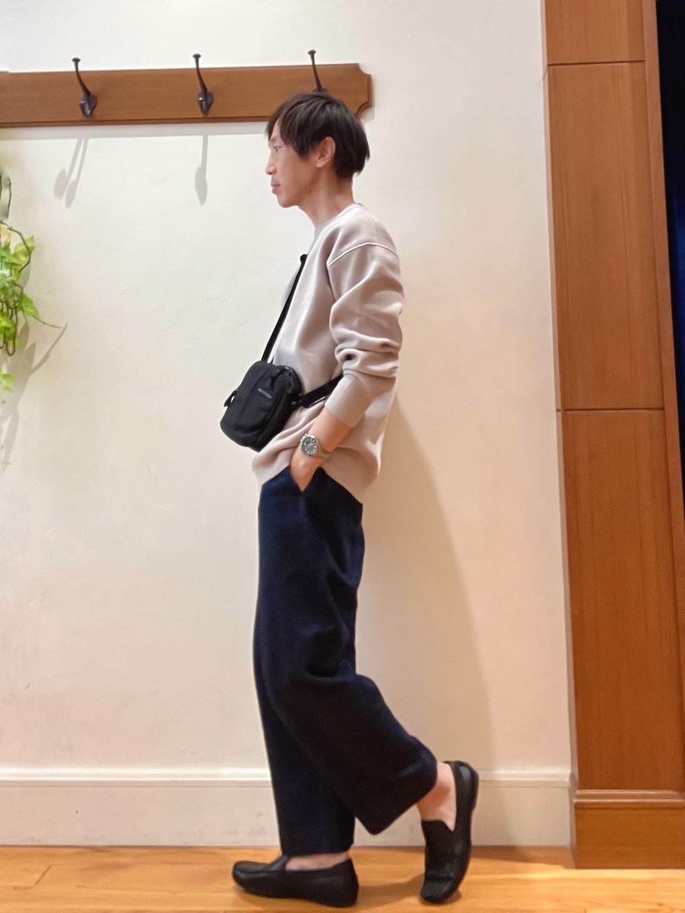 ブルー系のデニムパンツ、ブラック系のショルダーバッグ、ベージュ系のニット/セーターを着用したメンズの秋コーディネートの3枚目の写真