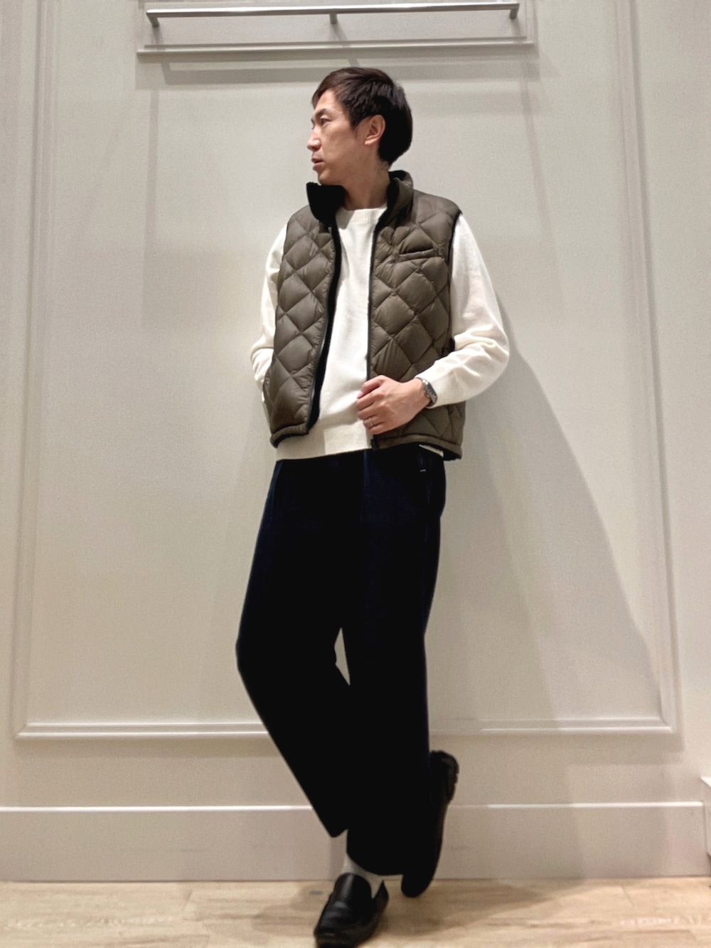 グリーン系のダウンベスト、ホワイト系のニット/セーターを着用したメンズの冬コーディネートの2枚目の写真