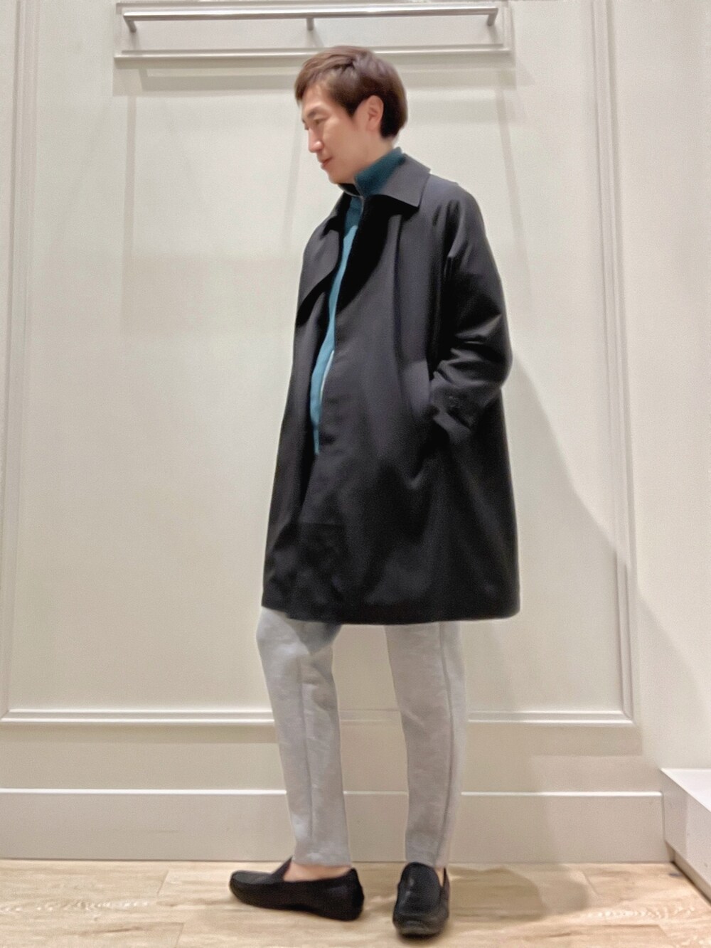 ブラック系のステンカラーコート、ブルー系のニット/セーター、グレー系のその他パンツを着用したメンズの春コーディネートの3枚目の写真