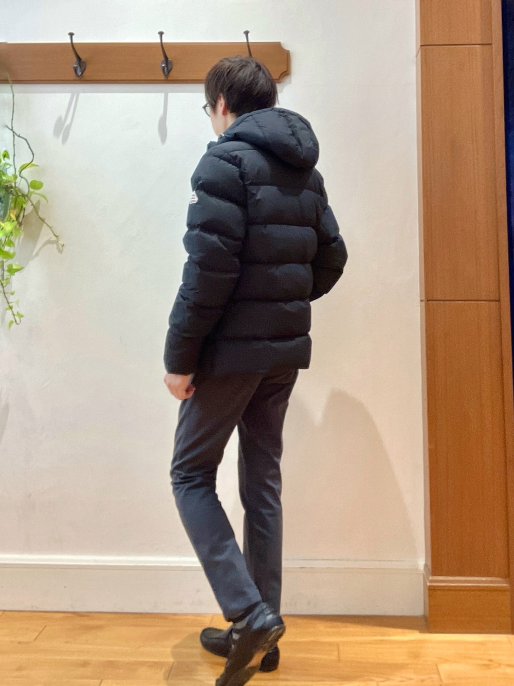 グレー系のチノパンツ、ブラック系のニット/セーター、ブラック系のダウンジャケット/コートを着用したメンズの冬コーディネートの3枚目の写真