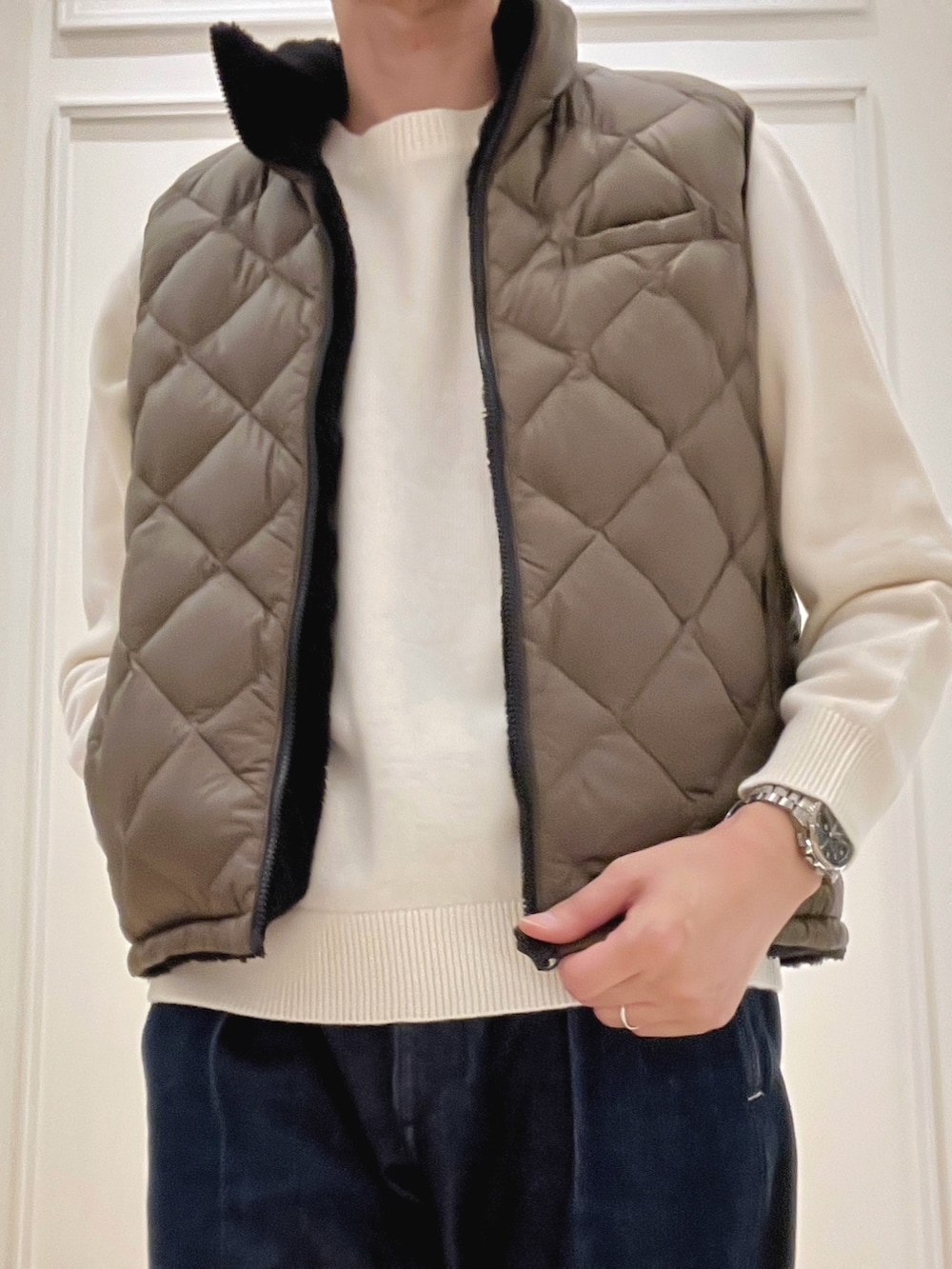 グリーン系のダウンベスト、ホワイト系のニット/セーターを着用したメンズの冬コーディネートの6枚目の写真