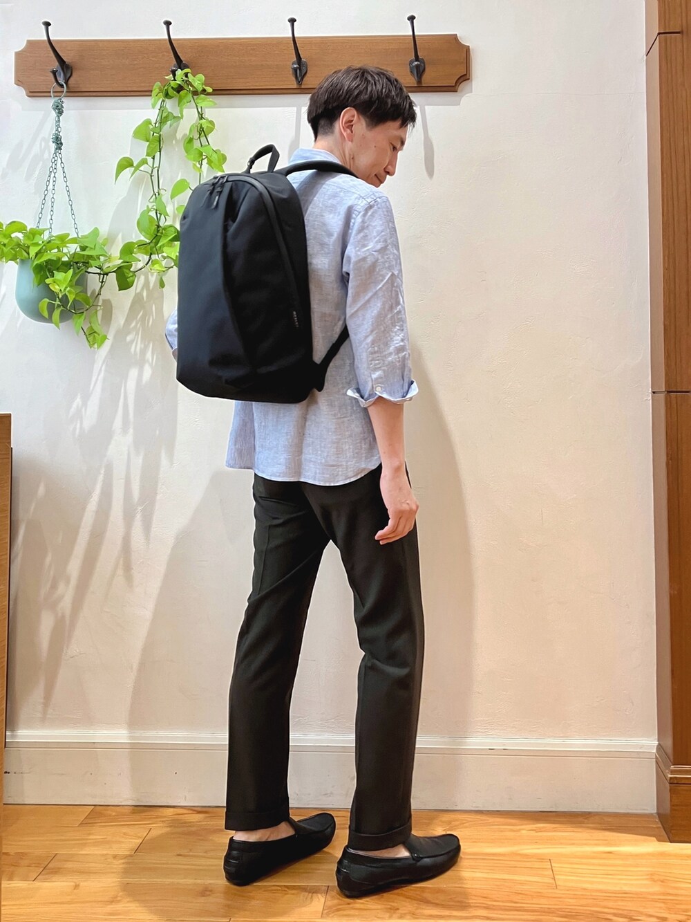 ブルー系のシャツ/ブラウス、ブラウン系のスラックス、ブラック系のバックパック/リュックを着用したメンズの春コーディネートの4枚目の写真