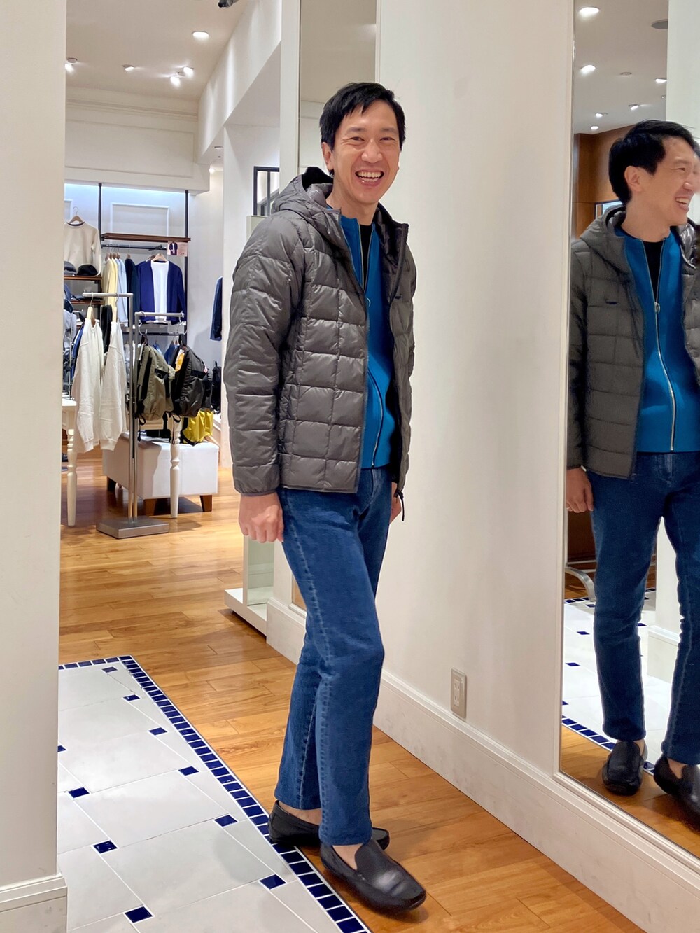 ブルー系のカーディガン/ボレロ、グレー系のダウンジャケット/コート、ブルー系のデニムパンツを着用したメンズの秋コーディネートの7枚目の写真