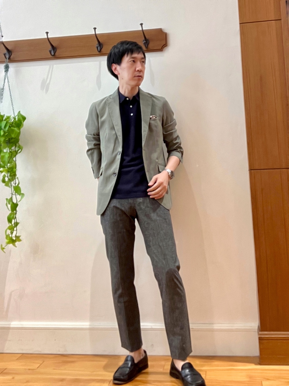 グリーン系のテーラードジャケット、ブラック系のポロシャツ、グレー系のその他パンツを着用したメンズの春コーディネートの2枚目の写真