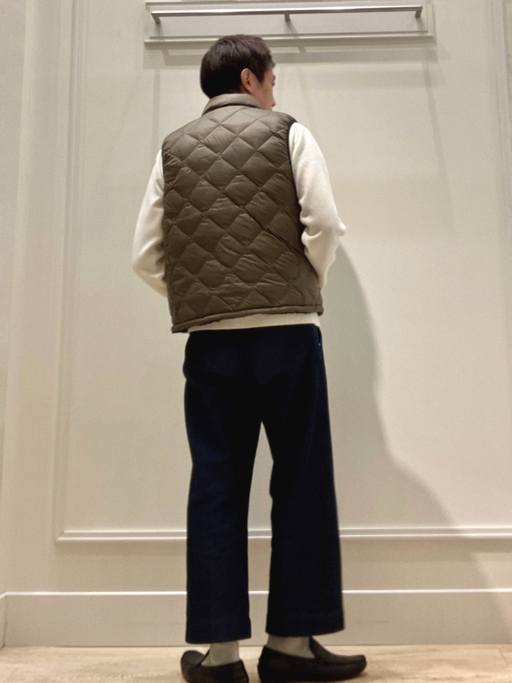 グリーン系のダウンベスト、ホワイト系のニット/セーターを着用したメンズの冬コーディネートの4枚目の写真