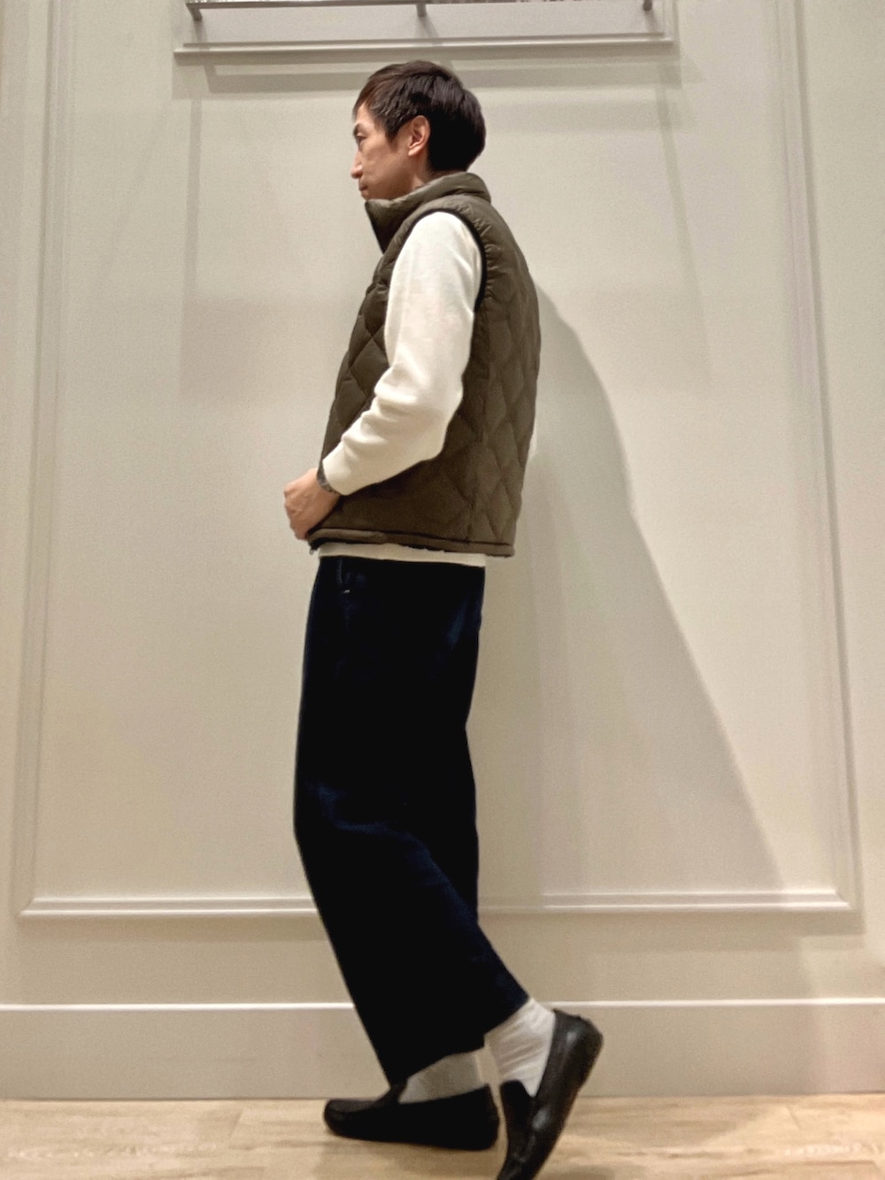 グリーン系のダウンベスト、ホワイト系のニット/セーターを着用したメンズの冬コーディネートの3枚目の写真