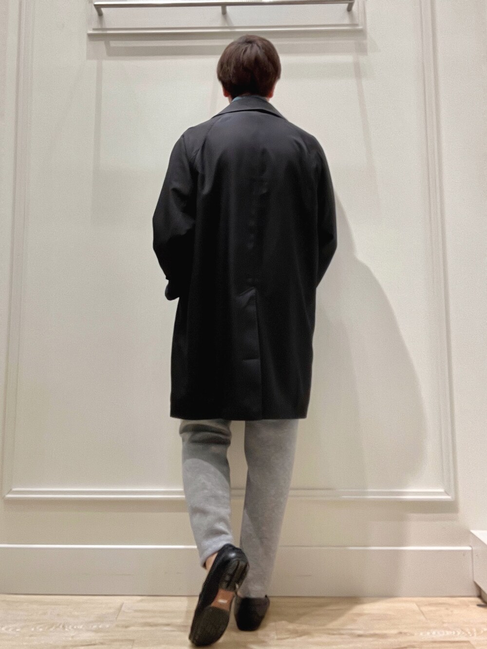 ブラック系のステンカラーコート、ブルー系のニット/セーター、グレー系のその他パンツを着用したメンズの春コーディネートの5枚目の写真
