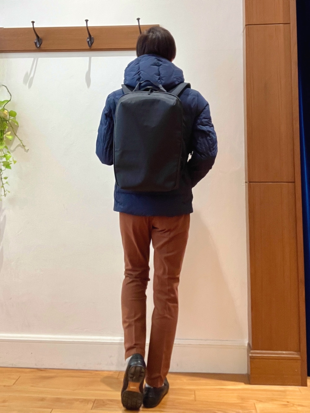 ブルー系のダウンジャケット/コート、イエロー系のチノパンツ、ブラック系のバックパック/リュックを着用したメンズの冬コーディネートの5枚目の写真