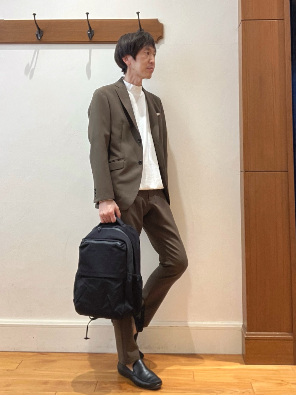ブラウン系のテーラードジャケット、ブラック系のバックパック/リュック、ブラウン系のその他パンツを着用したメンズの春コーディネートの8枚目の写真