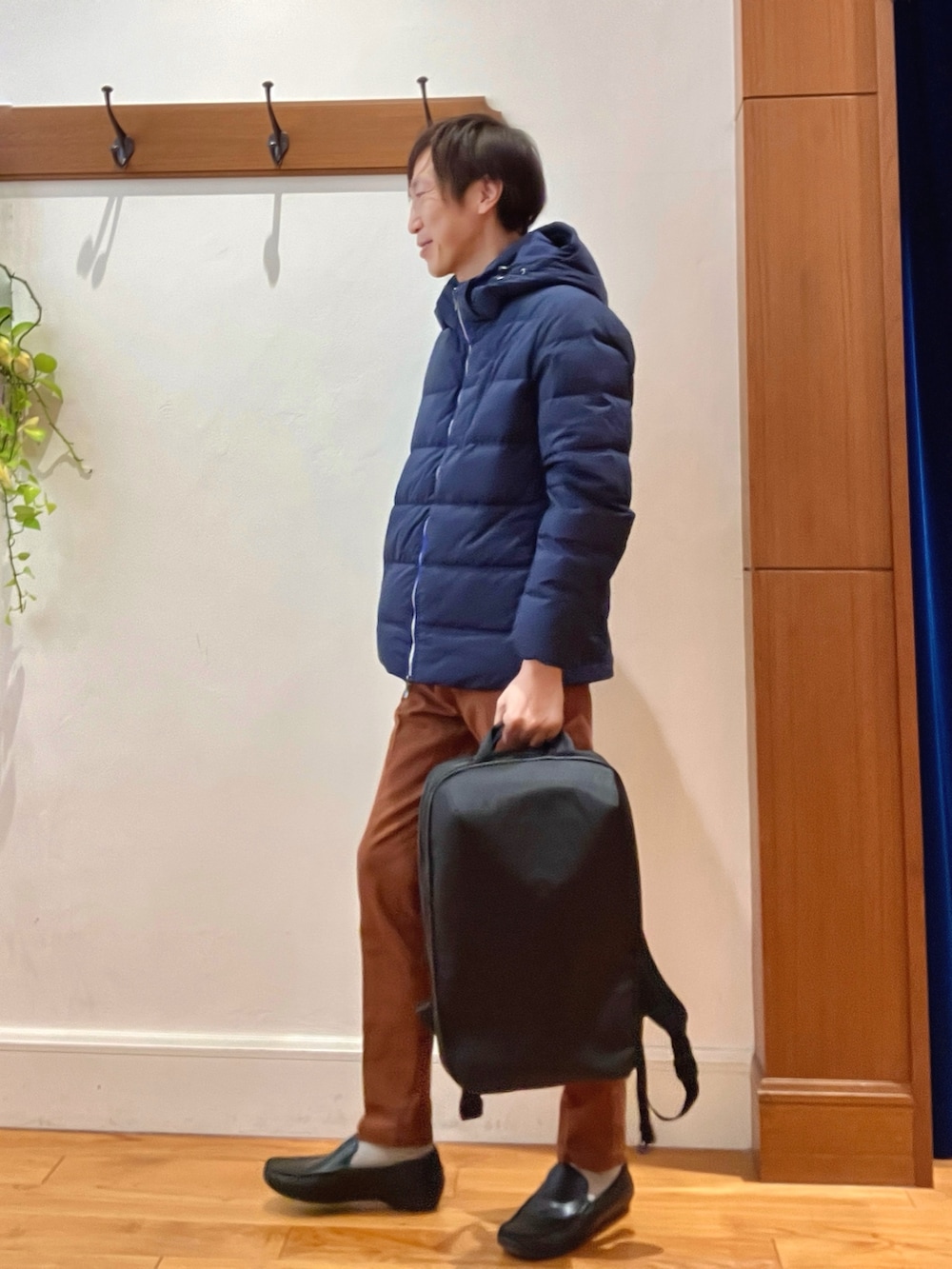 ブルー系のダウンジャケット/コート、イエロー系のチノパンツ、ブラック系のバックパック/リュックを着用したメンズの冬コーディネートの2枚目の写真