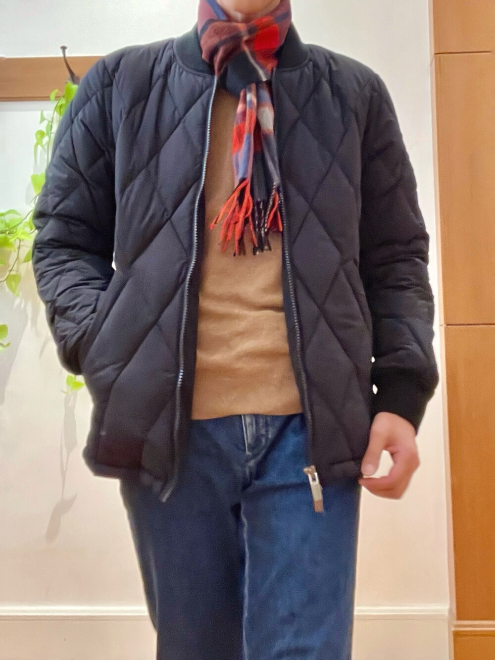 ブラック系のダウンジャケット/コート、ベージュ系のニット/セーター、ブルー系のデニムパンツを着用したメンズの冬コーディネートの8枚目の写真