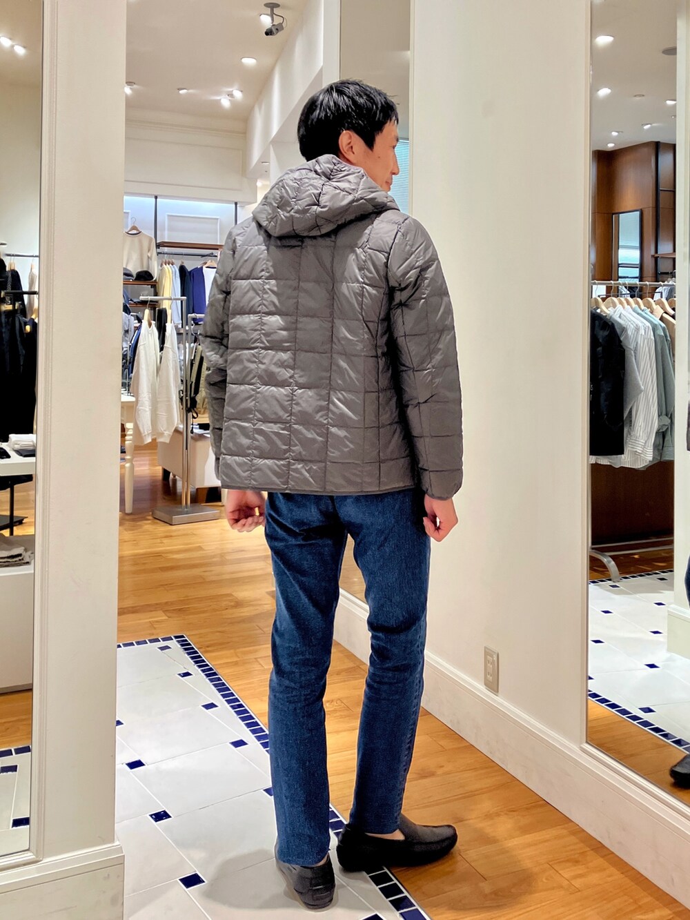 ブルー系のカーディガン/ボレロ、グレー系のダウンジャケット/コート、ブルー系のデニムパンツを着用したメンズの秋コーディネートの5枚目の写真