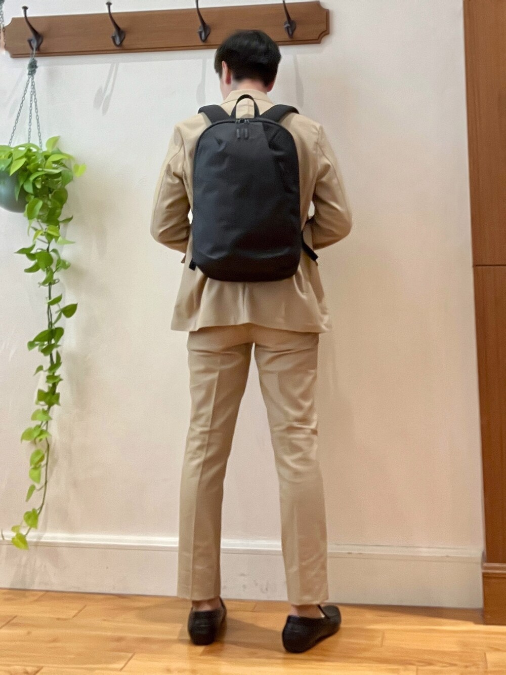 ベージュ系のテーラードジャケット、ブラック系のTシャツ/カットソー、ブラック系のバックパック/リュックを着用したメンズの秋コーディネートの4枚目の写真
