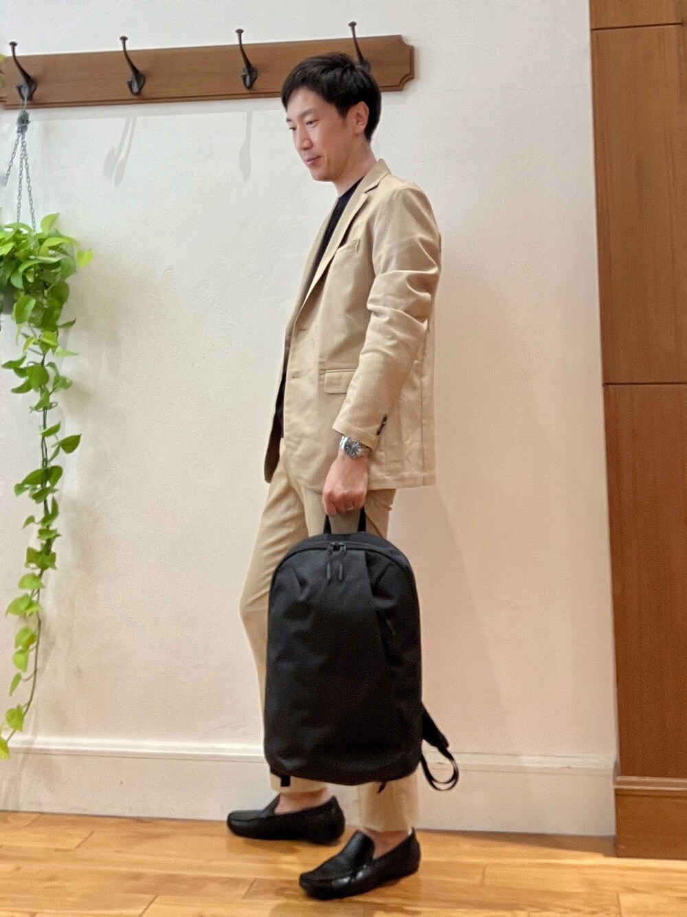 ベージュ系のテーラードジャケット、ブラック系のTシャツ/カットソー、ブラック系のバックパック/リュックを着用したメンズの秋コーディネートの3枚目の写真