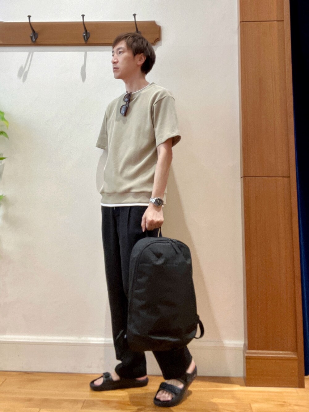 ブラック系のバックパック/リュック、ベージュ系のTシャツ/カットソー、ブラック系のサンダルを着用したメンズの夏コーディネートの2枚目の写真