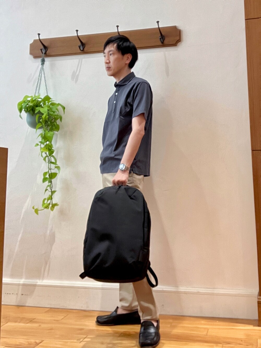 グレー系のポロシャツ、ブラック系のバックパック/リュック、ベージュ系のその他パンツを着用したメンズの春コーディネートの3枚目の写真