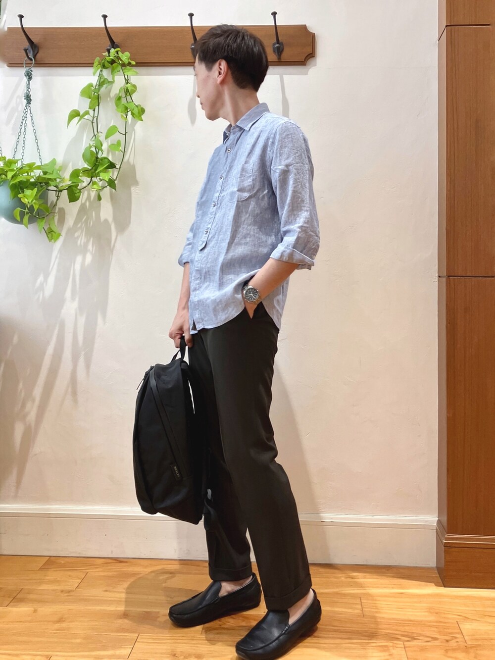 ブルー系のシャツ/ブラウス、ブラウン系のスラックス、ブラック系のバックパック/リュックを着用したメンズの春コーディネートの3枚目の写真