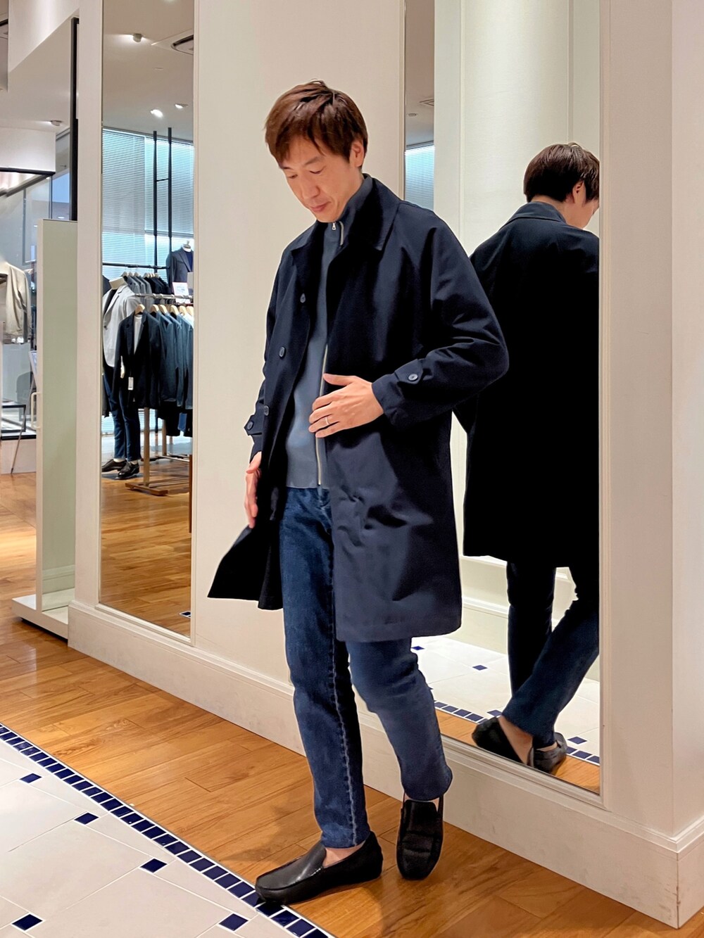 ブルー系のニット/セーター、ブルー系のステンカラーコート、ブルー系のデニムパンツを着用したメンズの秋コーディネートの4枚目の写真
