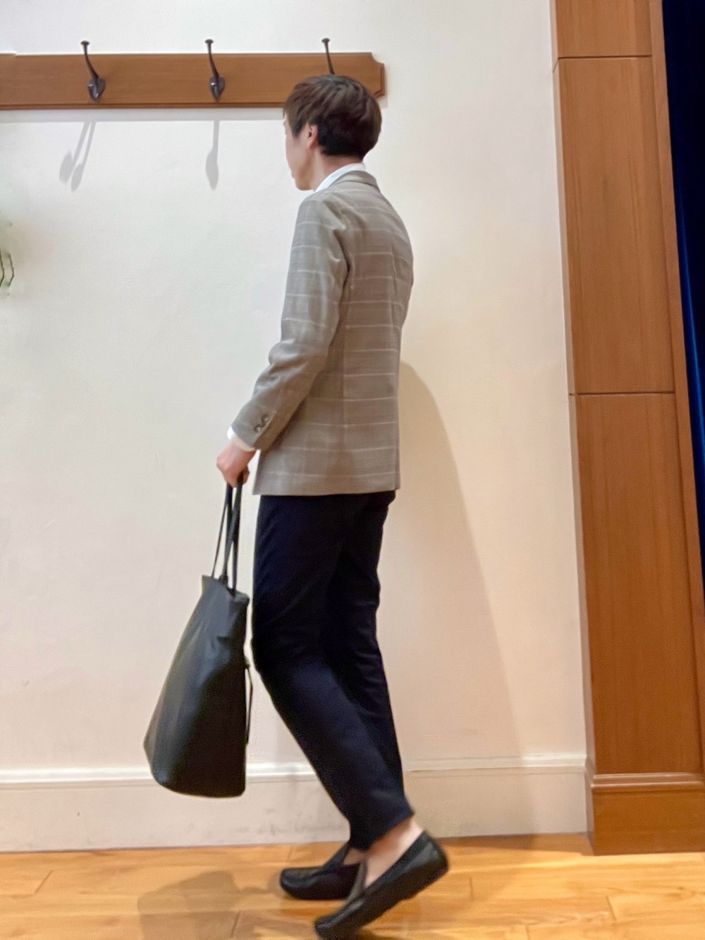 ブラック系のトートバッグ、ブルー系のチノパンツ、ブラウン系のテーラードジャケットを着用したメンズの夏コーディネートの4枚目の写真