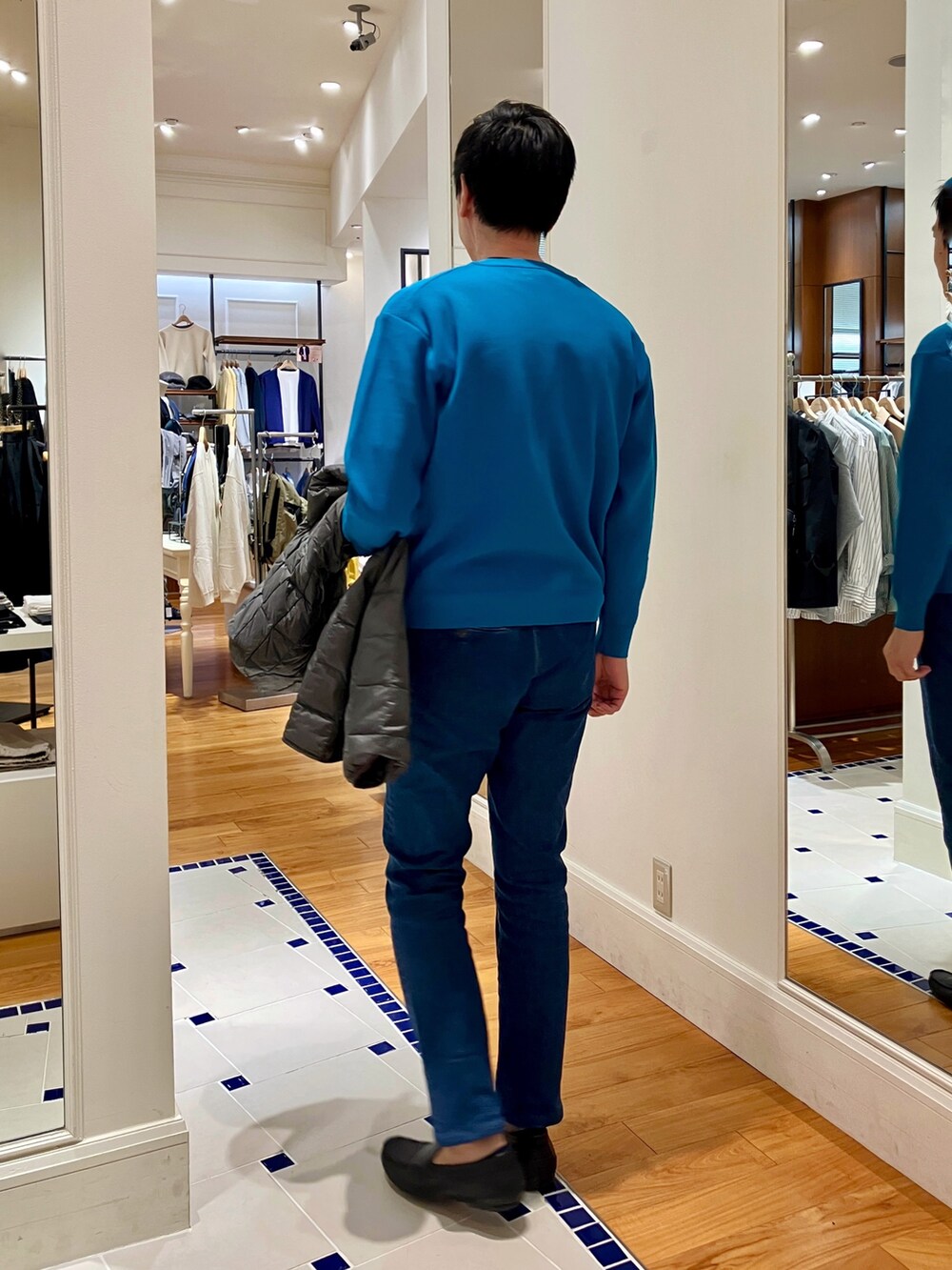 ブルー系のカーディガン/ボレロ、グレー系のダウンジャケット/コート、ブルー系のデニムパンツを着用したメンズの秋コーディネートの9枚目の写真