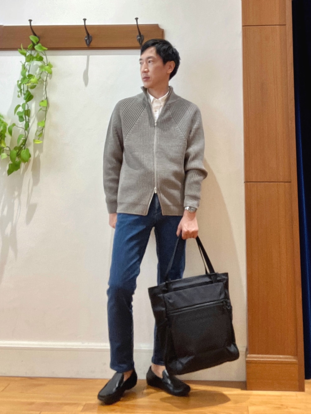 グレー系のニット/セーター、ホワイト系のシャツ/ブラウス、ブルー系のデニムパンツを着用したメンズの秋コーディネートの7枚目の写真