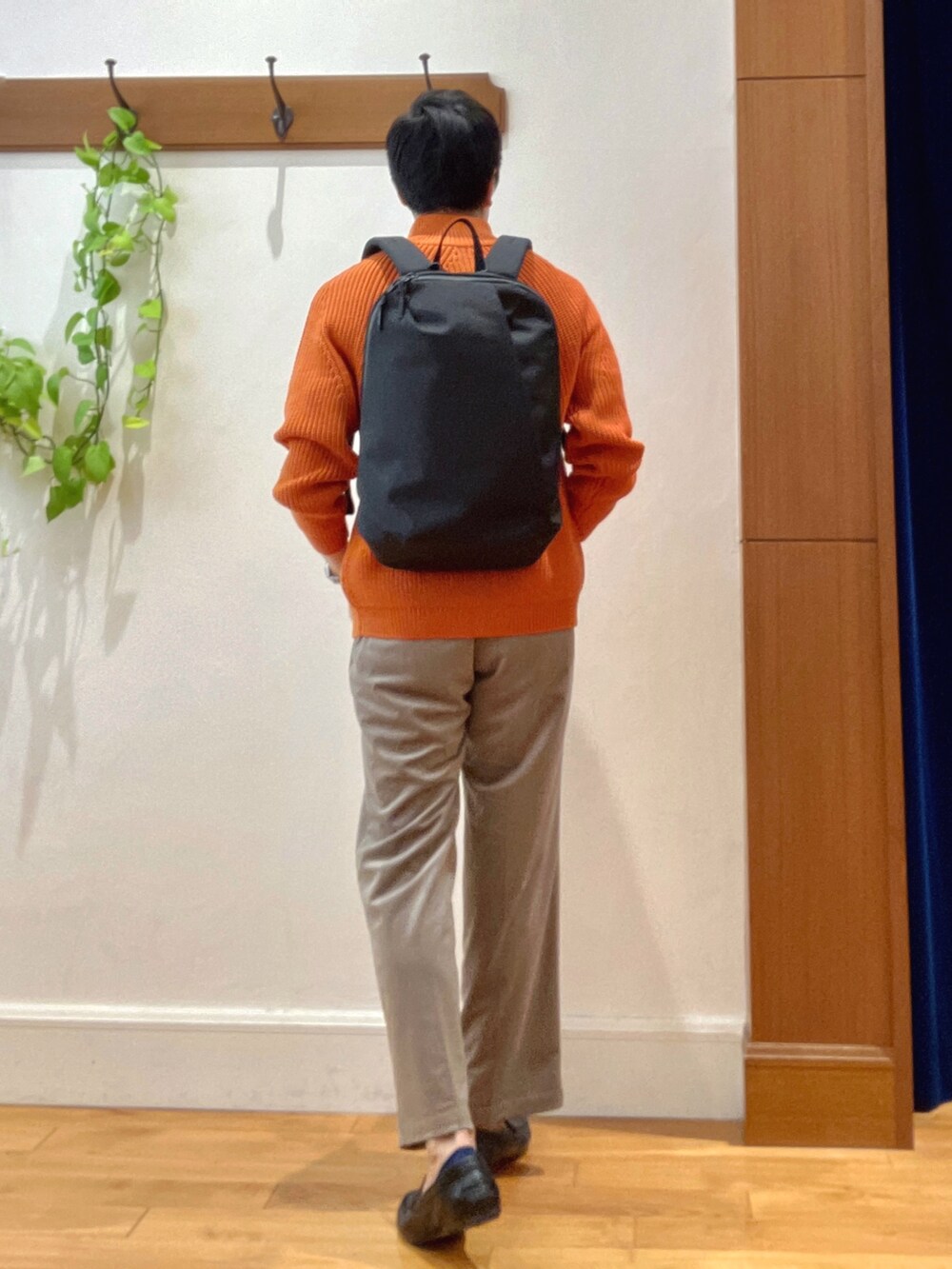 オレンジ系のニット/セーター、ブラック系のバックパック/リュック、ホワイト系のTシャツ/カットソーを着用したメンズの秋コーディネートの4枚目の写真