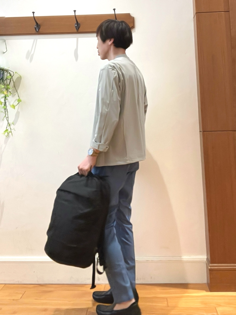 ブラック系のバックパック/リュック、ブルー系のチノパンツ、ブルー系のTシャツ/カットソーを着用したメンズの春コーディネートの3枚目の写真
