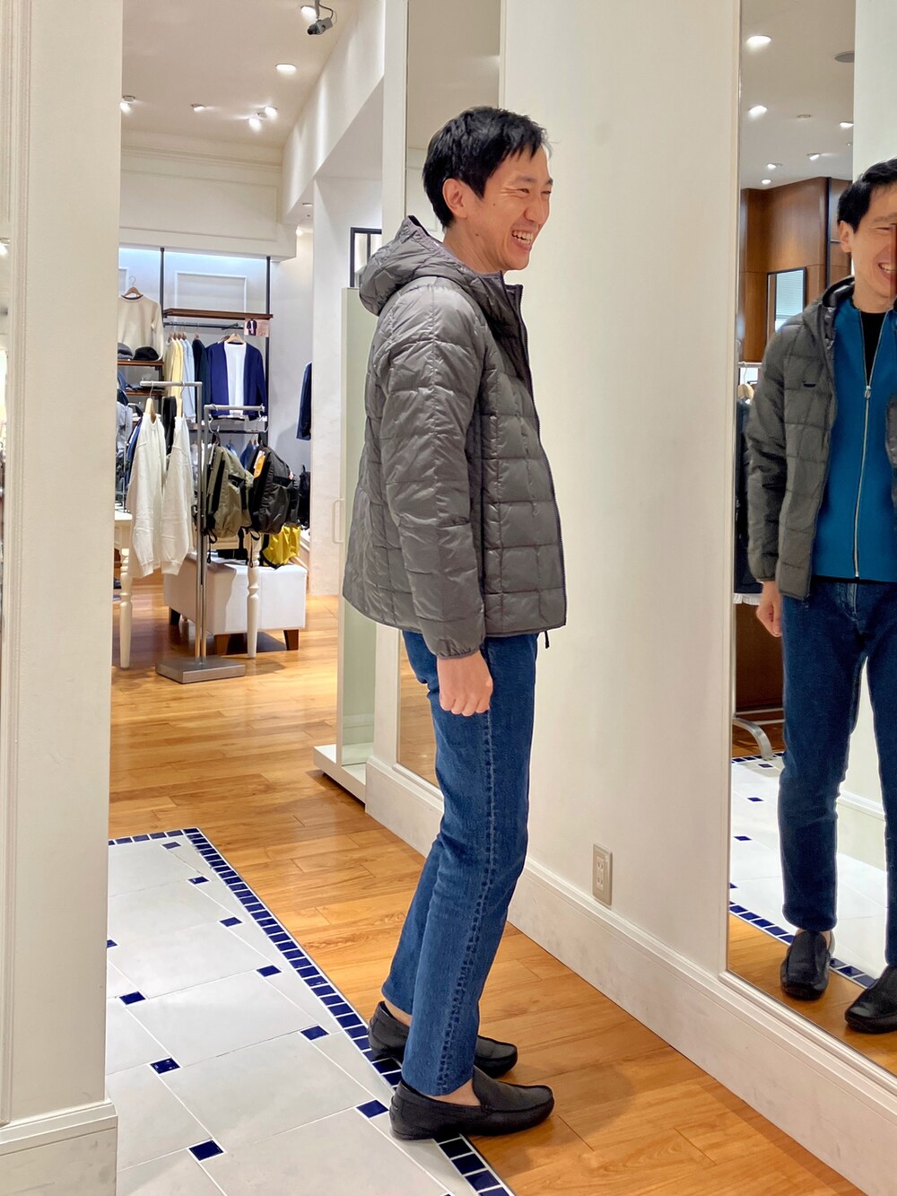 ブルー系のカーディガン/ボレロ、グレー系のダウンジャケット/コート、ブルー系のデニムパンツを着用したメンズの秋コーディネートの6枚目の写真