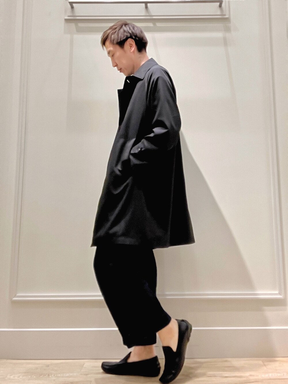 ブラック系のステンカラーコート、グリーン系のニット/セーターを着用したメンズの冬コーディネートの2枚目の写真