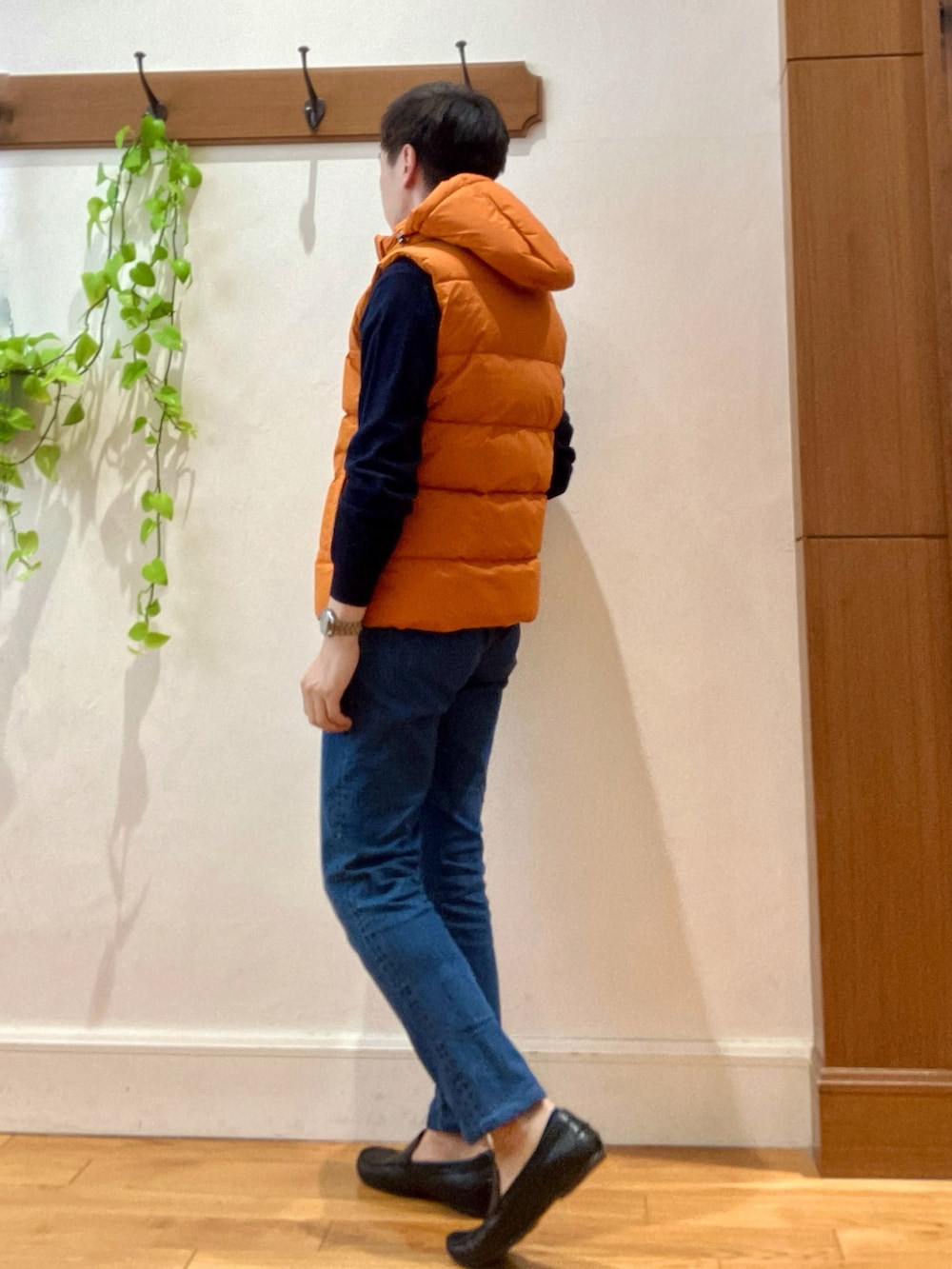 ブルー系のデニムパンツ、ブルー系のニット/セーター、オレンジ系のダウンベストを着用したメンズの冬コーディネートの4枚目の写真