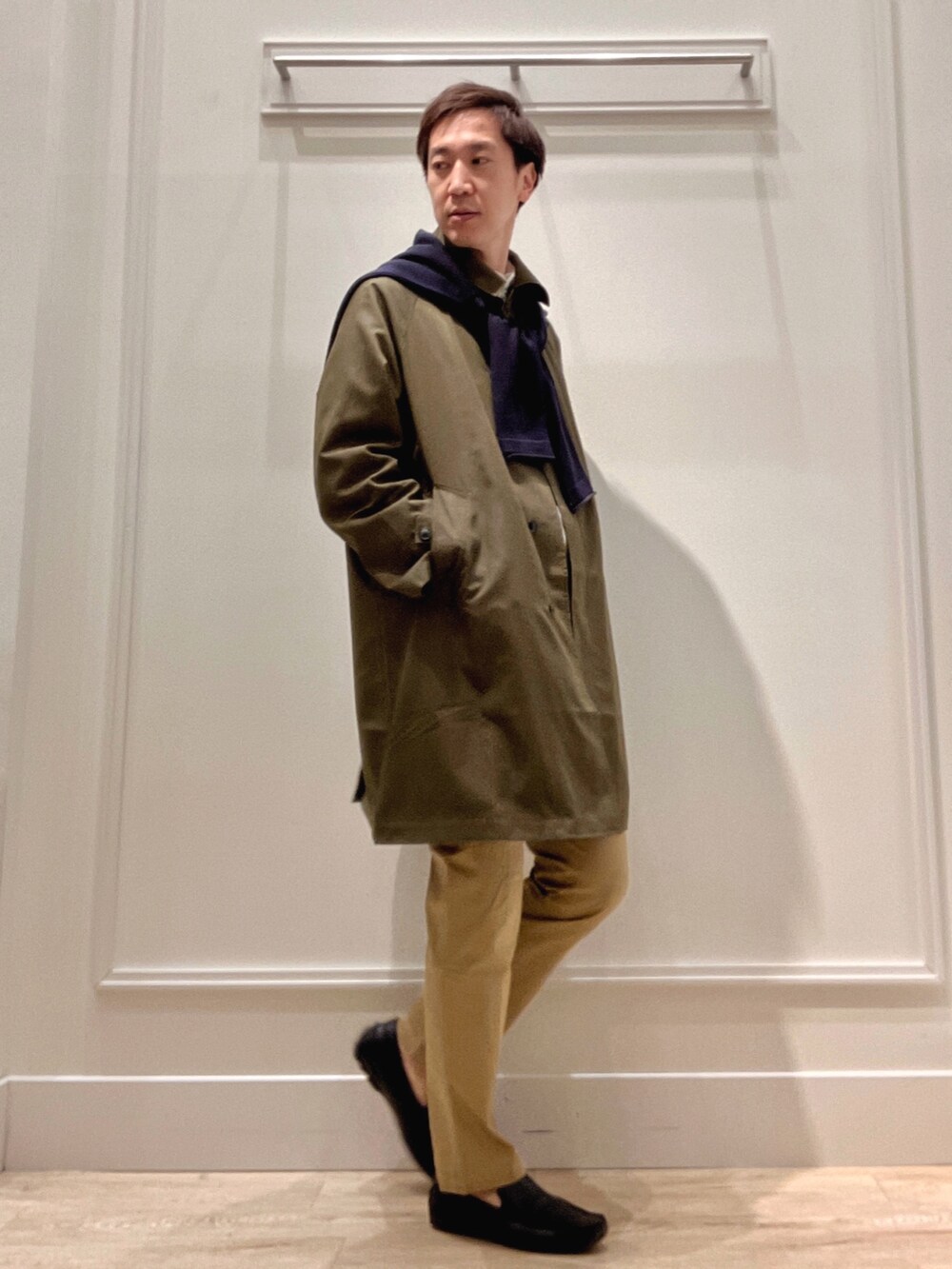 グリーン系のステンカラーコート、ベージュ系のチノパンツ、ブルー系のカーディガン/ボレロを着用したメンズの冬コーディネートの6枚目の写真