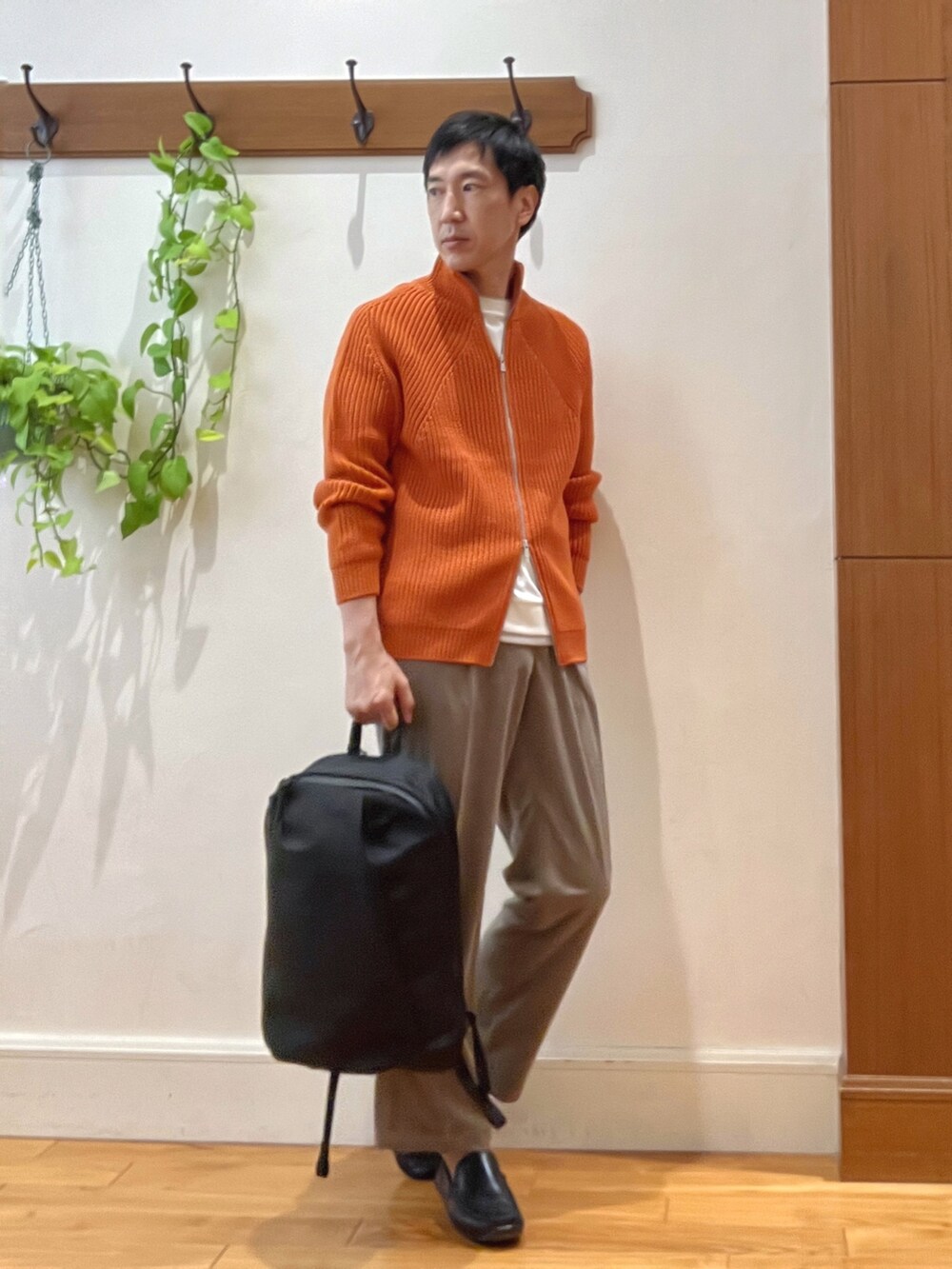 オレンジ系のニット/セーター、ブラック系のバックパック/リュック、ホワイト系のTシャツ/カットソーを着用したメンズの秋コーディネートの6枚目の写真