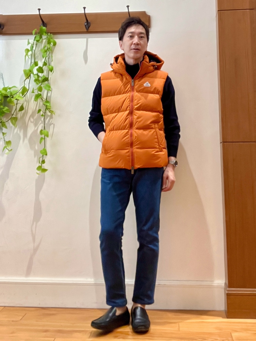 ブルー系のデニムパンツ、ブルー系のニット/セーター、オレンジ系のダウンベストを着用したメンズの冬コーディネートの8枚目の写真
