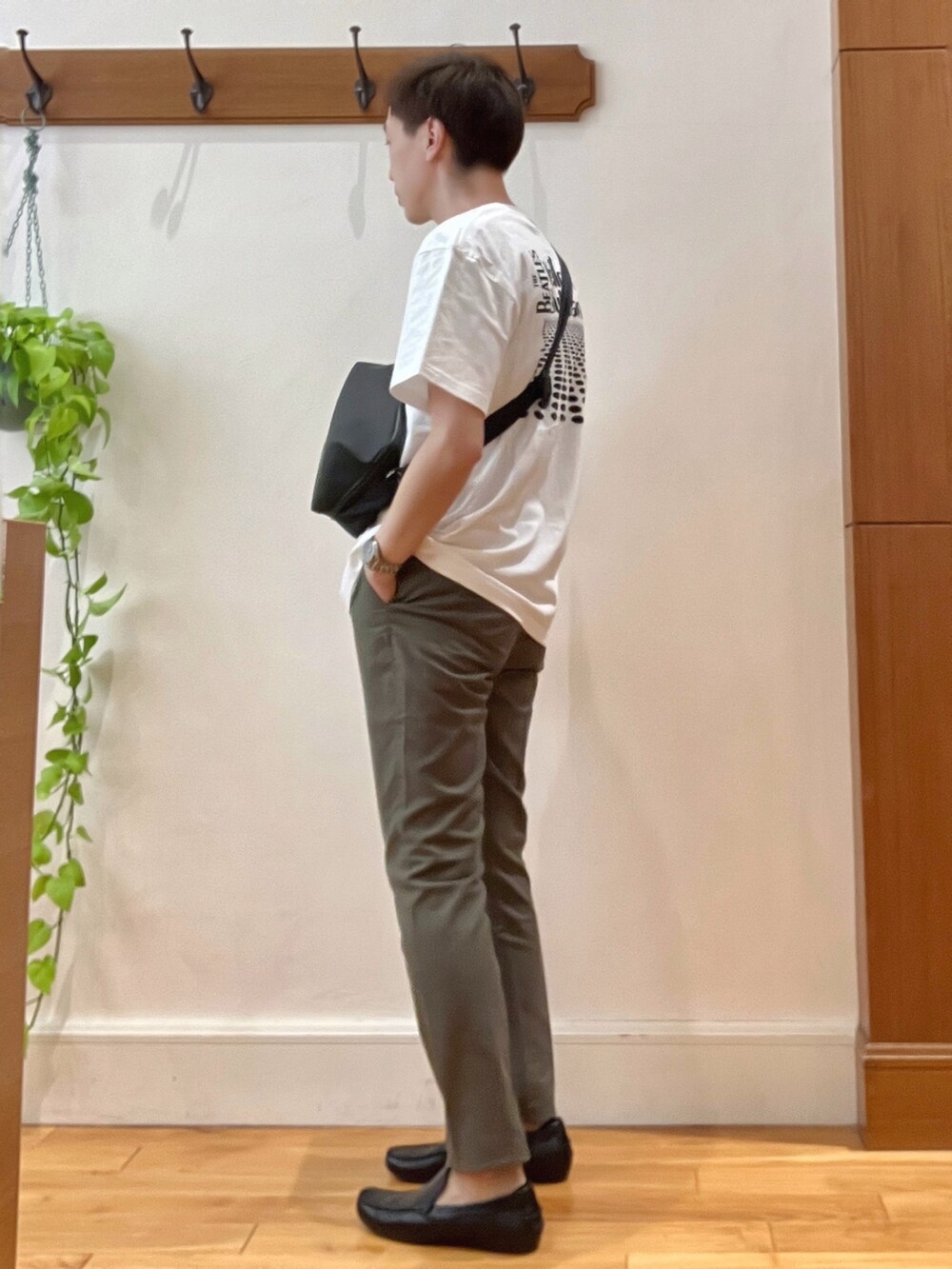 グリーン系のチノパンツ、ブラック系のショルダーバッグ、ホワイト系のTシャツ/カットソーを着用したメンズの春コーディネートの4枚目の写真