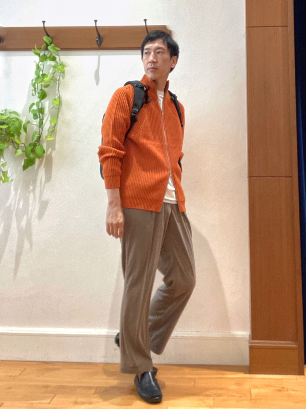 オレンジ系のニット/セーター、ブラック系のバックパック/リュック、ホワイト系のTシャツ/カットソーを着用したメンズの秋コーディネートの7枚目の写真