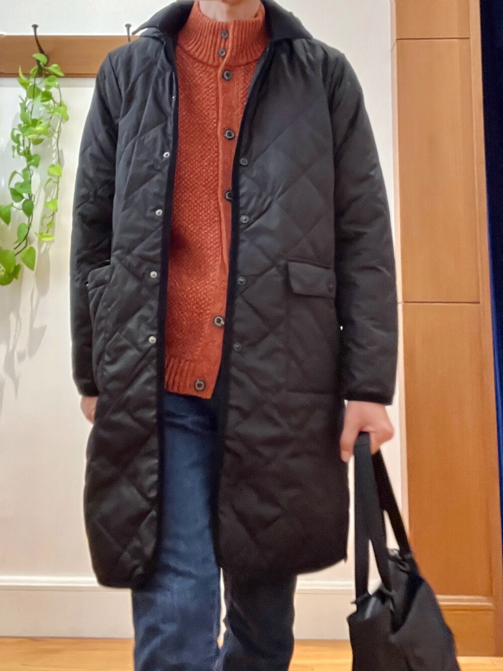 ブラック系のダウンジャケット/コート、オレンジ系のカーディガン/ボレロ、ブラック系のトートバッグを着用したメンズの秋コーディネートの9枚目の写真