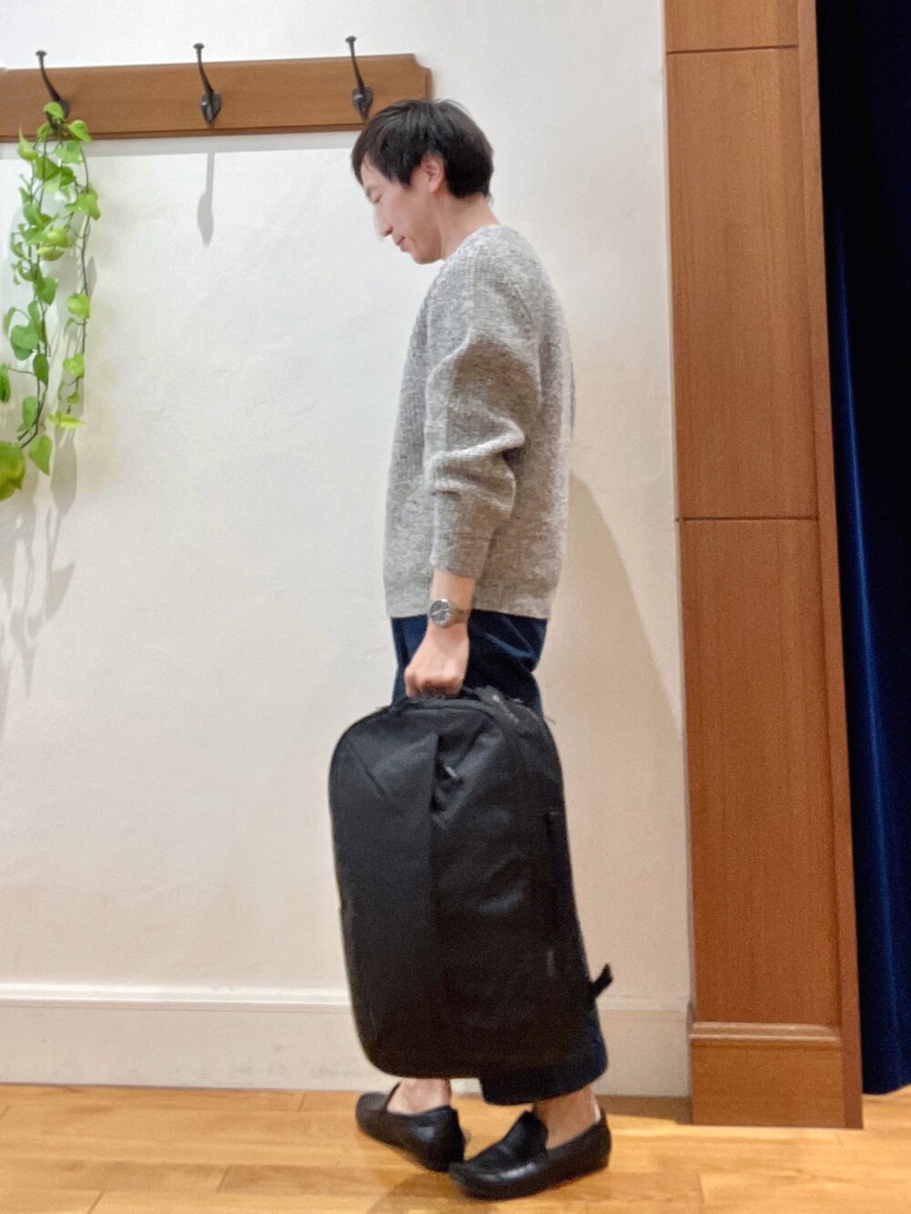グレー系のニット/セーター、ブラック系のバックパック/リュックを着用したメンズの秋コーディネートの2枚目の写真