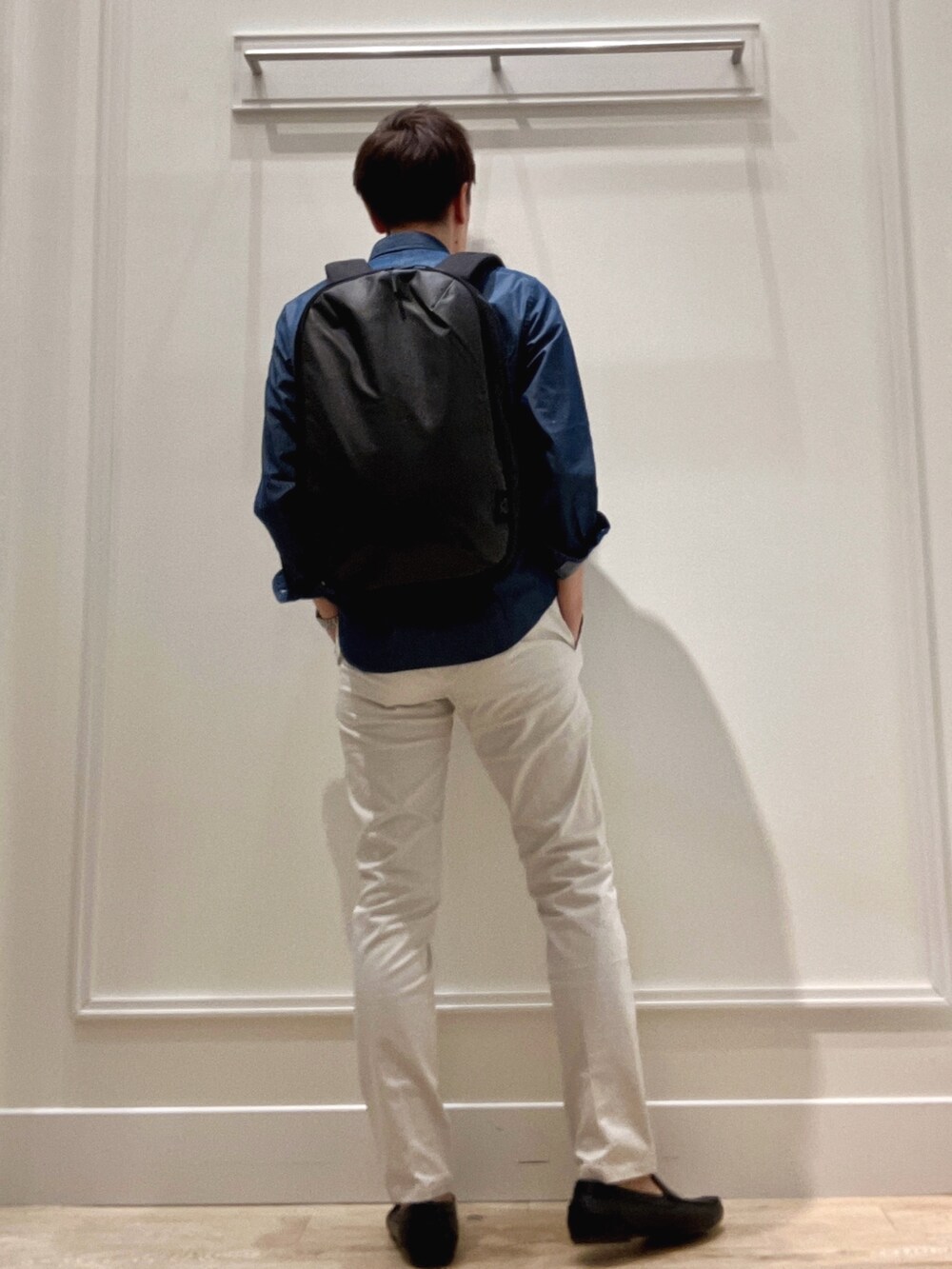 ブラック系のバックパック/リュック、グレー系のチノパンツ、ブルー系のシャツ/ブラウスを着用したメンズの冬コーディネートの5枚目の写真