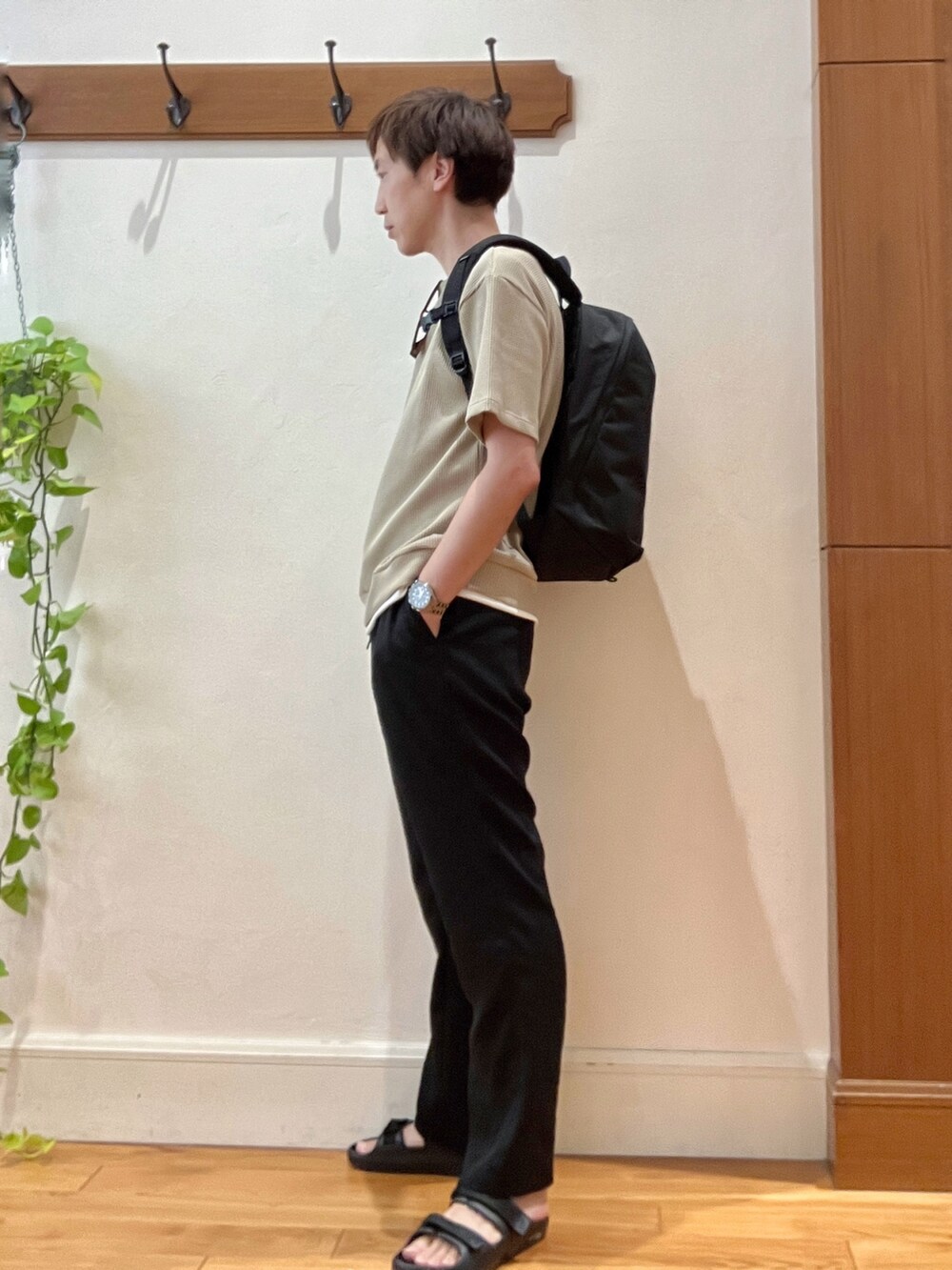 ブラック系のバックパック/リュック、ベージュ系のTシャツ/カットソー、ブラック系のサンダルを着用したメンズの夏コーディネートの3枚目の写真