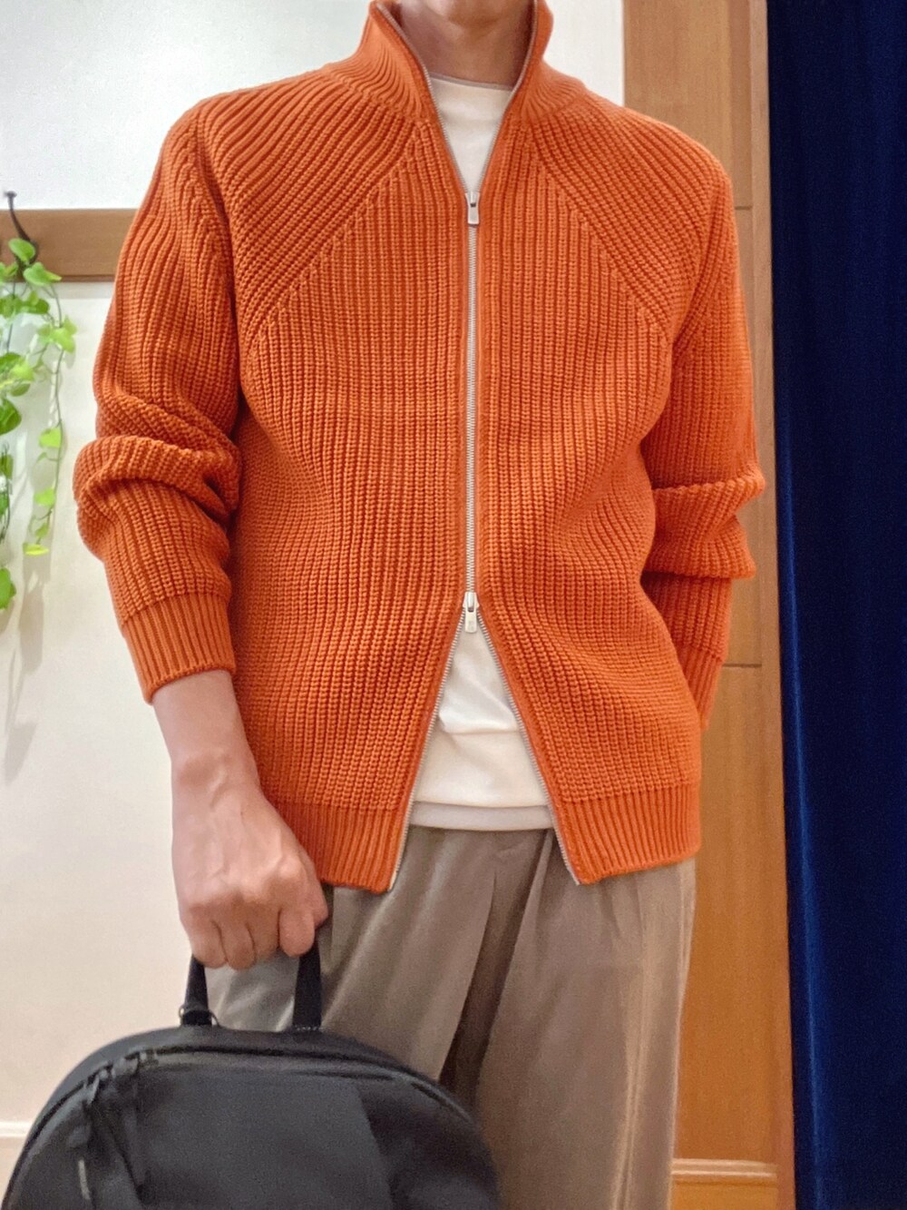 オレンジ系のニット/セーター、ブラック系のバックパック/リュック、ホワイト系のTシャツ/カットソーを着用したメンズの秋コーディネートの8枚目の写真