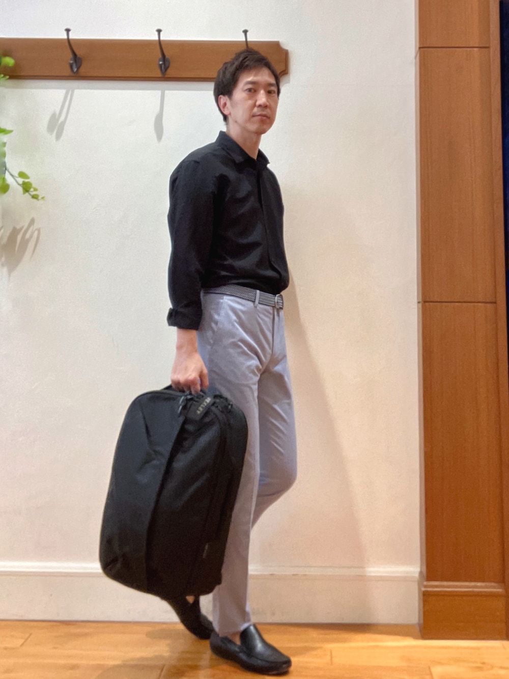 ブラック系のシャツ/ブラウス、ブルー系のチノパンツ、ブラック系のバックパック/リュックを着用したメンズの春コーディネートの6枚目の写真