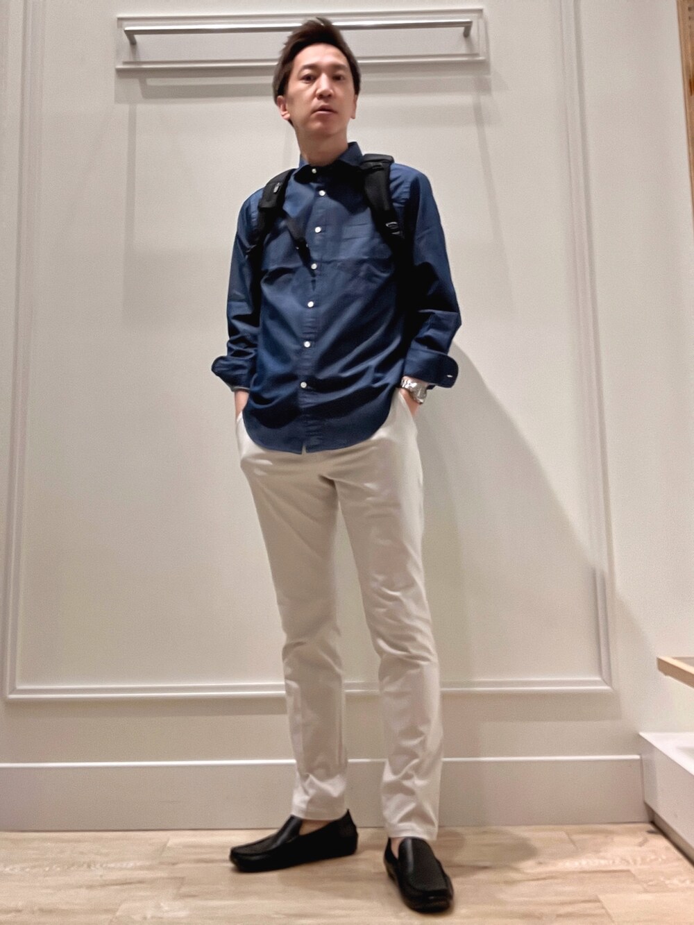 ブラック系のバックパック/リュック、グレー系のチノパンツ、ブルー系のシャツ/ブラウスを着用したメンズの冬コーディネートの2枚目の写真