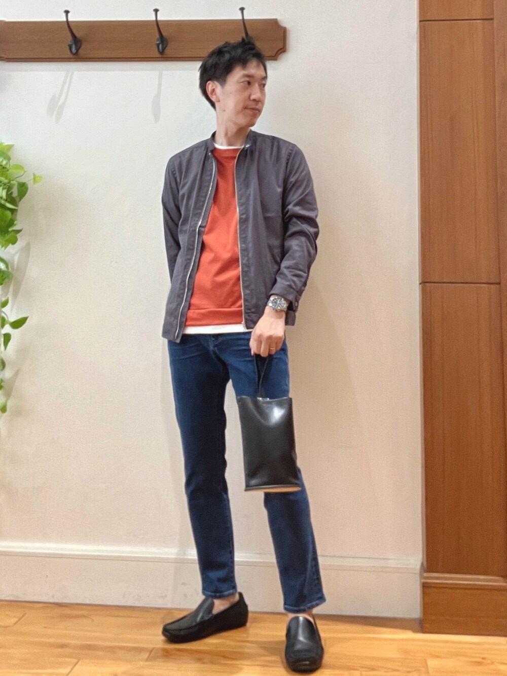 ブルー系のデニムパンツ、ブラック系のハンドバッグ、オレンジ系のTシャツ/カットソーを着用したメンズの秋コーディネートの2枚目の写真