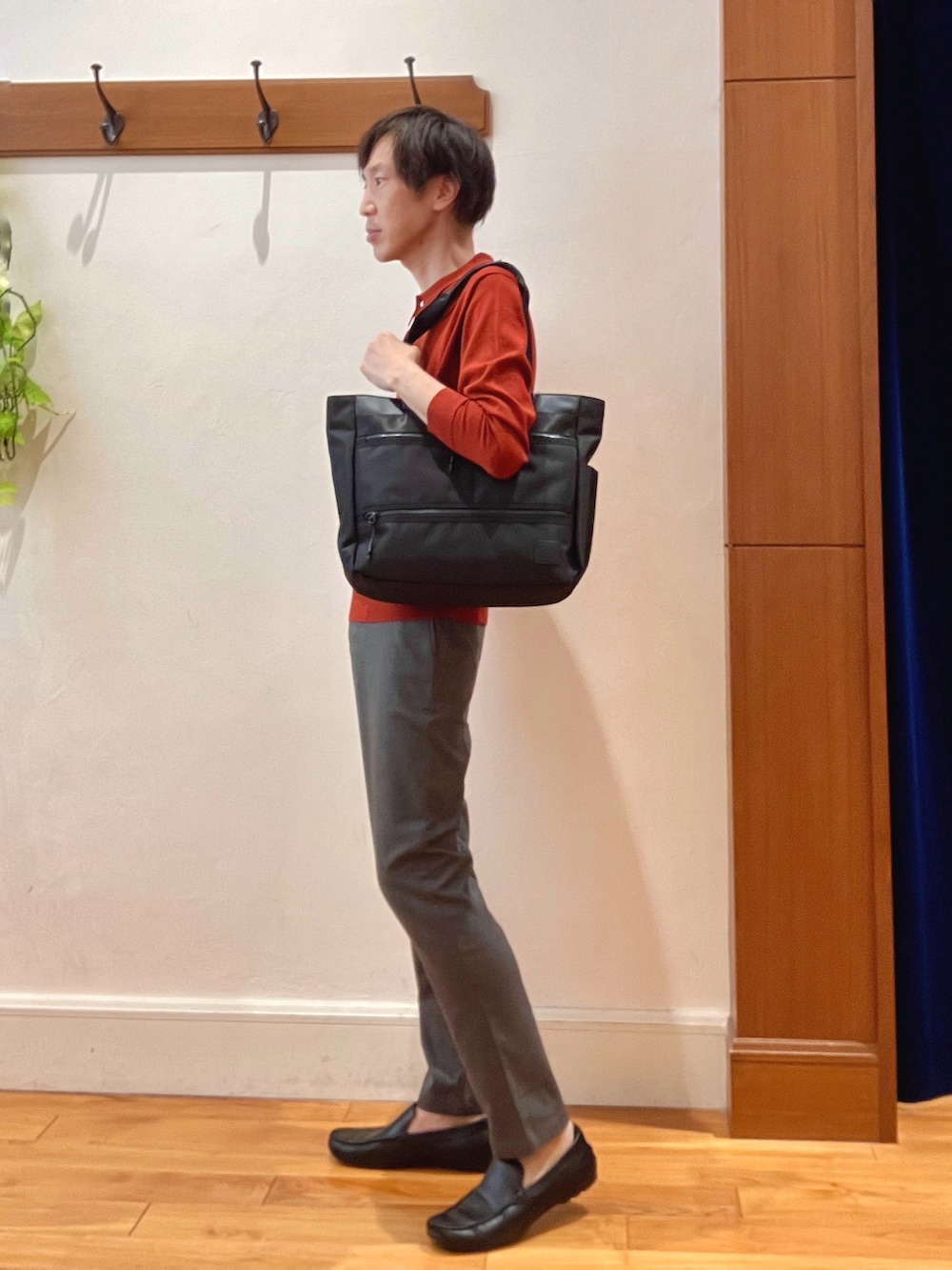 グレー系のその他パンツ、レッド系のニット/セーター、ブラック系のトートバッグを着用したメンズの秋コーディネートの2枚目の写真