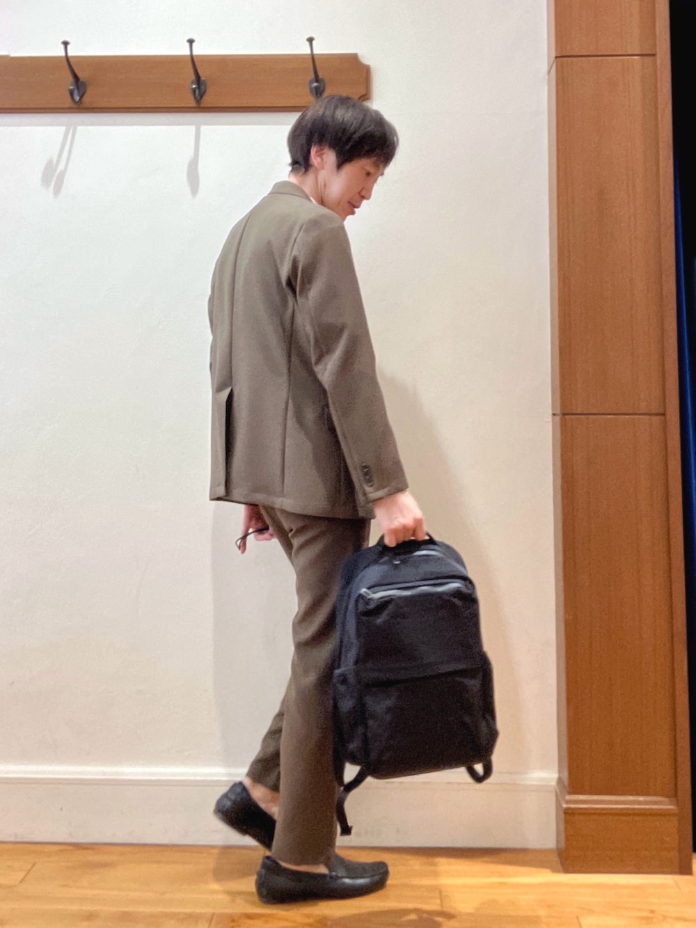 ブラウン系のテーラードジャケット、ブラック系のバックパック/リュック、ブラウン系のその他パンツを着用したメンズの春コーディネートの6枚目の写真