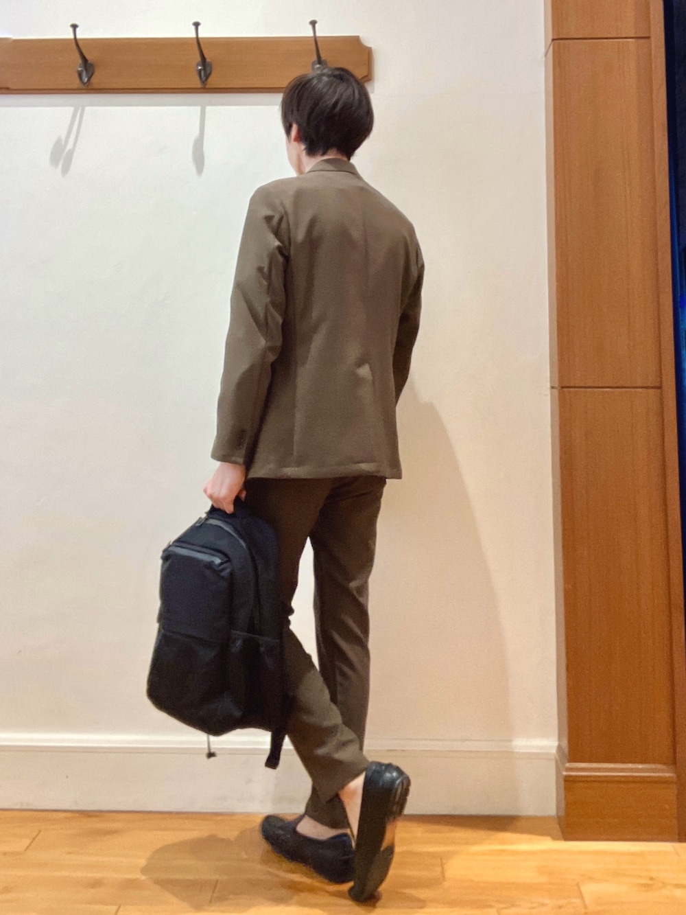 ブラウン系のテーラードジャケット、ブラック系のバックパック/リュック、ブラウン系のその他パンツを着用したメンズの春コーディネートの4枚目の写真