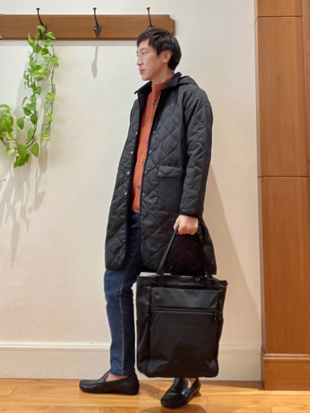 ブラック系のダウンジャケット/コート、オレンジ系のカーディガン/ボレロ、ブラック系のトートバッグを着用したメンズの秋コーディネートの3枚目の写真